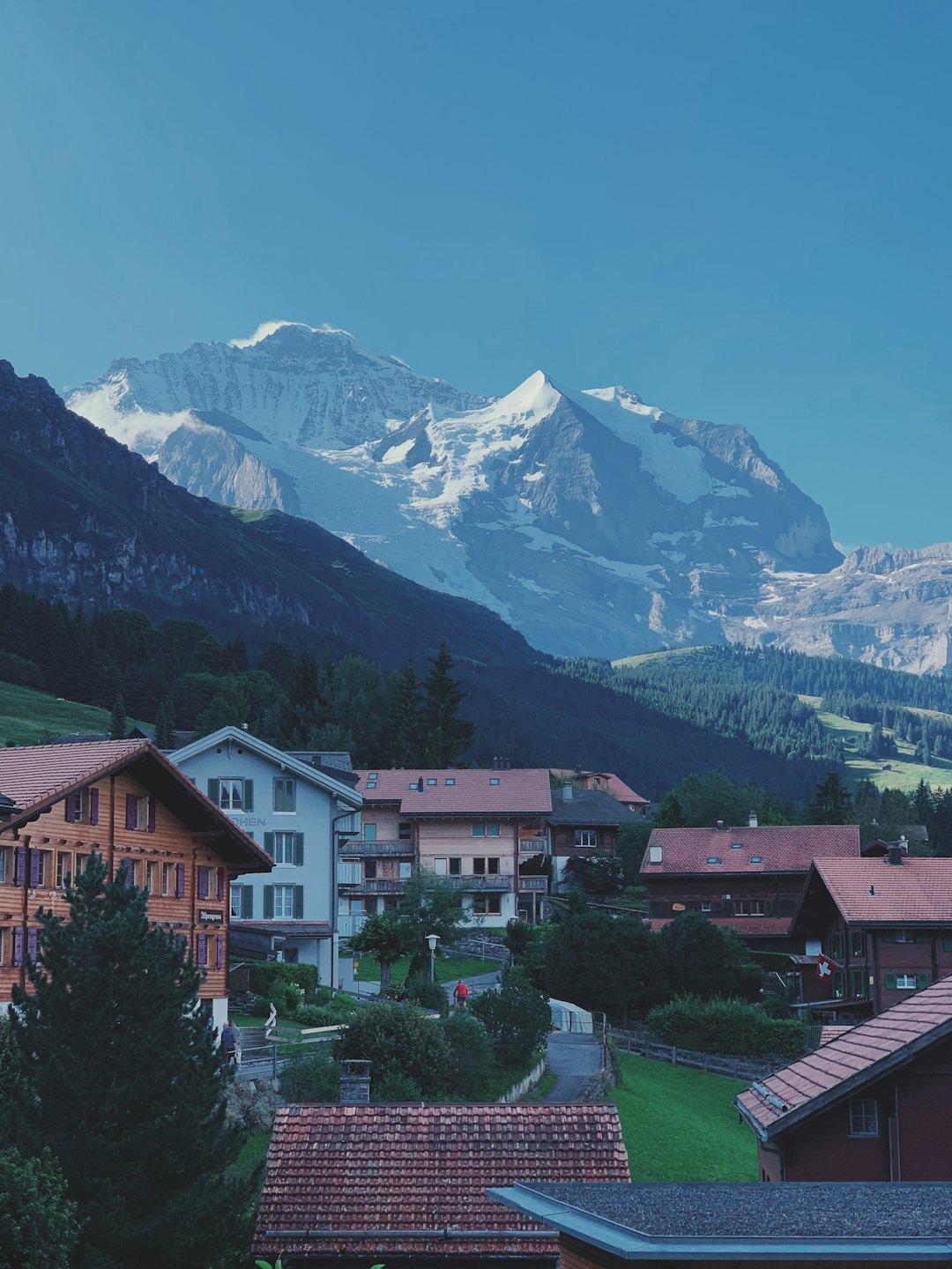 European village with wooden houses nestled among mountains and forests.