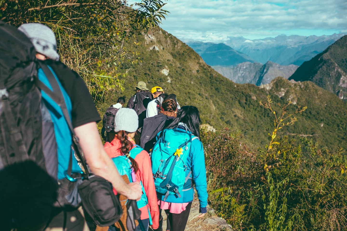Hikers on a rocky mountain trail surrounded by trees.