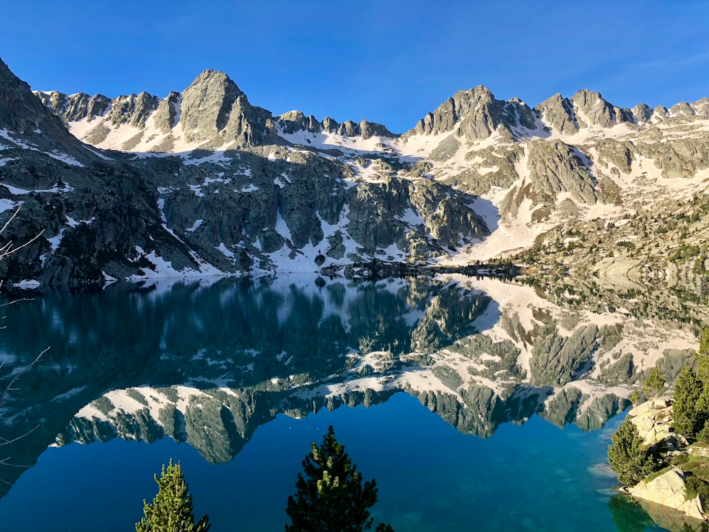 Snowy mountains reflect in the calm water of a lake.